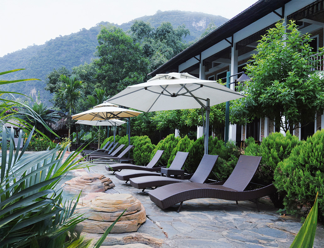 Khu vực thư giãn bên bể bơi với view núi